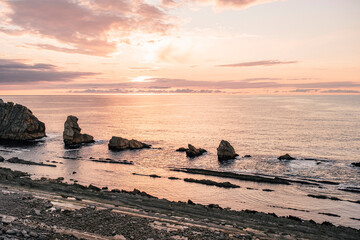 Fototapeta na wymiar Pink sunset in rocky coastline