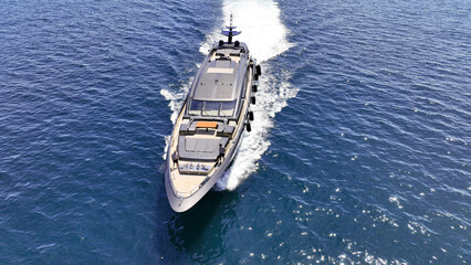 Aerial drone photo of beautiful yacht with wooden deck cruising in high speed deep blue Aegean sea...