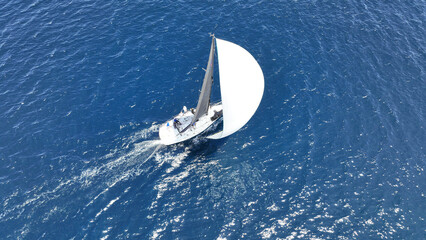 Aerial drone photo of beautiful sailing boat with white sails cruising deep blue Aegean sea, Greece