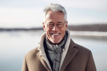 Fototapeta premium Lifestyle portrait photography of a grinning mature man wearing a cozy winter coat against a scenic lagoon background. With generative AI technology