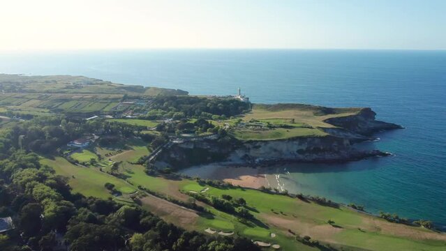 Aerial view of golf courses on the outskirts of Santander city. Beautiful sunset colours. In the center is Playa de Matale&ntilde;as, an beautiful small beach. In background Lighthouse Cabo Mayor. Descending