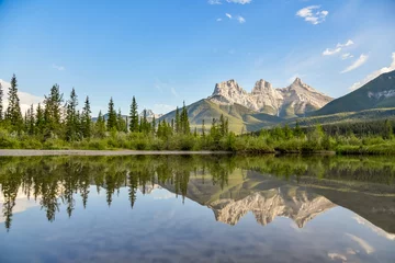 Photo sur Plexiglas Réflexion Incredible view of Three Sisters in Canada, Banff National Park with mountains reflecting in calm, lake, water below blue sky, pristine, perfect wilderness setting. 