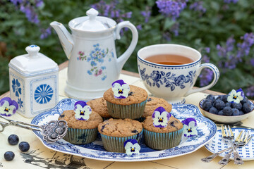 vegane Heidelbeer-Apfel-Muffins auf einem Teller und weiß-blaues Teegeschirr
