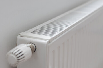 White heater with radiator and a modern thermostat on the wall in an apartment