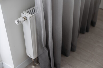 White heater with radiator and a modern thermostat on the wall in an apartment
