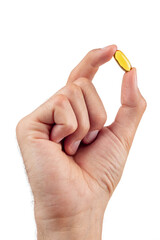 Man's hand holding a pill of fish oil, isolated on a white background.