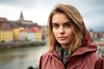 Photography in the style of pensive portraiture of a glad mature girl wearing a lightweight windbreaker against a picturesque old town background. With generative AI technology