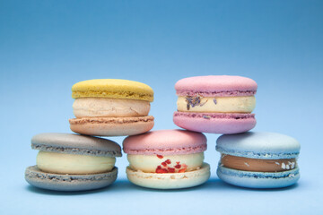 Five different colors macaroons cakes on blue background, card with dessert and sweet food