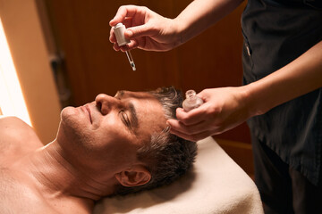 Obraz na płótnie Canvas Experienced masseuse preparing client for facial massage