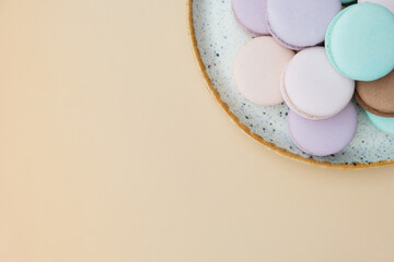 Different pastel colors pastry macaroons top view on a beige background with copy space