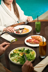 Two people eating by swimming pool in wellness center