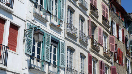 Fototapeta na wymiar Wide angle view on colourful classical facades with windows shutters and tiny balconies downtown Bayonne, French Basque country, France