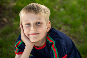 Portrait of a little boy in a blue t-shirt posing in a summer park