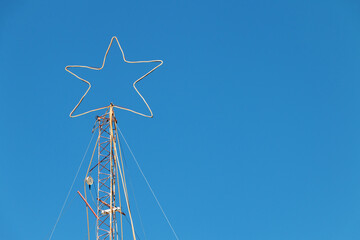 A white star in christmas street lights on at top of column in a clear blue sky background