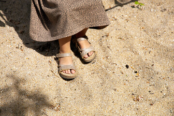 Feet of a littel girl in sandals on the sand