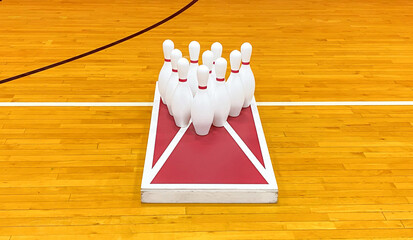 Bowling pins on a cornhole game board in a gym for gym class