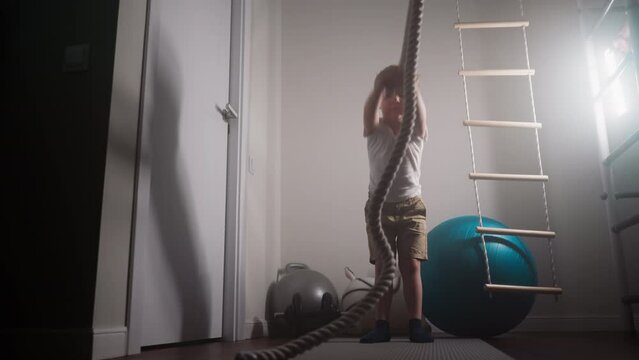Motivated toddler tries workout with battle rope in hands