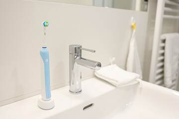 Electric toothbrush on white sink in bathroom