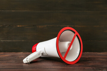 Megaphone with prohibition sign on dark wooden background. Censorship concept