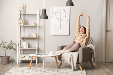 Young woman sitting in soft armchair at home