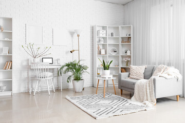 Stylish interior of light living room with modern laptop on table