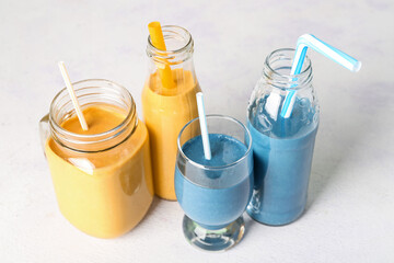 Glasses and bottles of colorful smoothie on white background