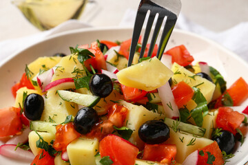 Bowl of tasty Potato Salad with vegetables on table, closeup