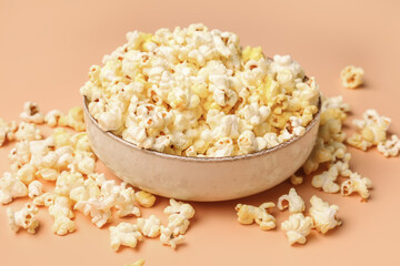 Bowl with crispy popcorn on beige background