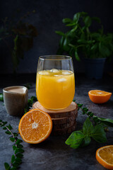 Orange juice with espresso shot and ice, bumble bee with basil leaves on dark background 