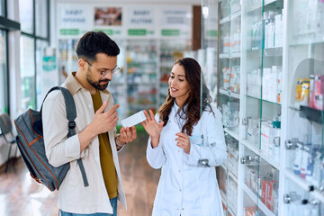 Smiling pharmacist assists her customer in choosing vitamins in pharmacy.