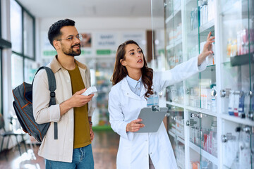 Happy man buying in drugstore with help of females pharmacist.