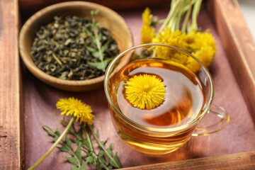 Glass cup of healthy dandelion tea on wooden board