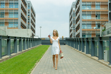 PRETTY BLONDE GIRL WALKING WITH GLASSES AND A BAG IN HER HAND