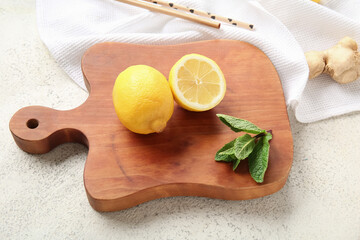 Wooden board with lemons, ginger and mint on grunge white background