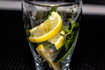 Cucumber infused detox water in a glass. Homemade flavored lemonade. Fresh cucumber water with basil and lemon in glasses on wooden table