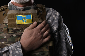Mature soldier with Ukrainian patch on dark background, closeup