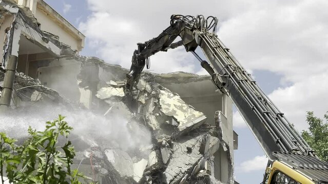 Demolition by a demolition machine. Spraying water to prevent dust formation. 