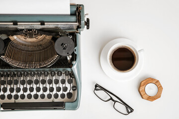 Vintage typewriter with cup of coffee, eyeglasses and candle on white background