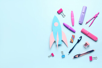 Paper rocket with different stationery on blue background