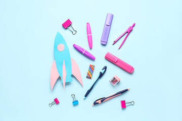 Paper rocket with different stationery on blue background