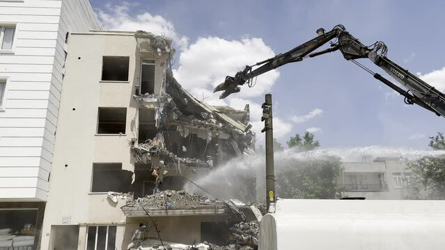 A demolition machine and a tanker that sprays water to prevent dust formation.
