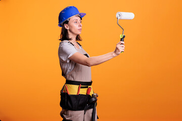 Woman renovator painting walls with roller brush doing interior renovation, working on home improvement. Professional construction worker holding paintbrush and roll to redecorate.