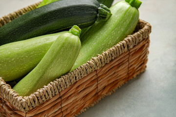 Wicker tray with fresh zucchini on light background