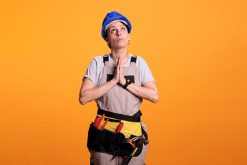 Female building engineer doing prayer hands symbol on camera, begging and asking for new renovation projects. Woman construction worker hoping to work on building site and renovation project.