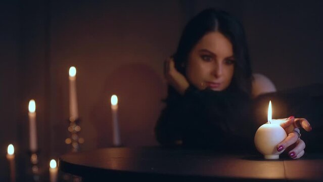 A witch performs a rite or a love spell in a dark room with burning candles