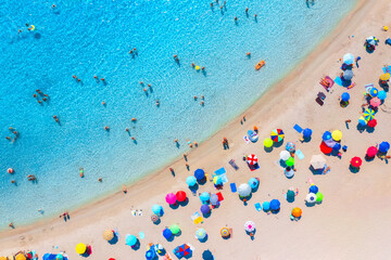 Fototapeta na wymiar Aerial view of colorful umbrellas on sandy beach, swimming people in blue sea at summer sunny day. Sardinia, Italy. Tropical seascape with clear azure water. Travel and vacation. Top drone view