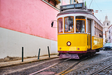 Famous vintage yellow tram 28 in the narrow streets of Alfama district in Lisbon, Portugal - symbol of Lisbon, famous popular travel destination and tourist attraction