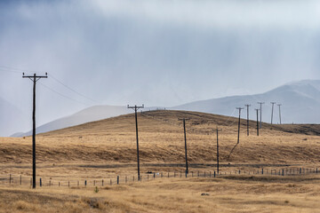 Photograph of telephone poles running through a valley against snow capped mountains on the South Island of New Zealand