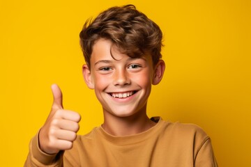 Headshot portrait photography of a grinning boy in his 20s showing a thumb up against a mustard yellow background. With generative AI technology