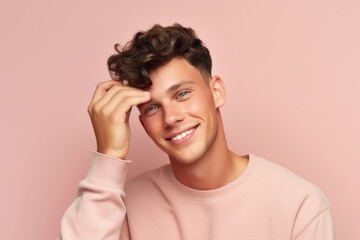 Medium shot portrait photography of a grinning boy in his 30s putting the hand on the forehead to look for someone in the distance against a pastel pink background. With generative AI technology